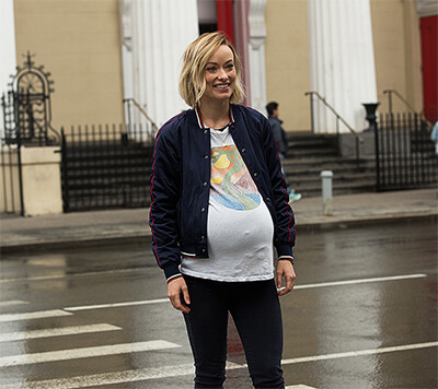 A Pregnant Abby stands on a zebra-crossing, smiling at someone off-camera.