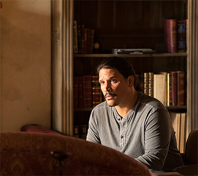 Javier sits, relaxed but concerned, in a country-house chair.