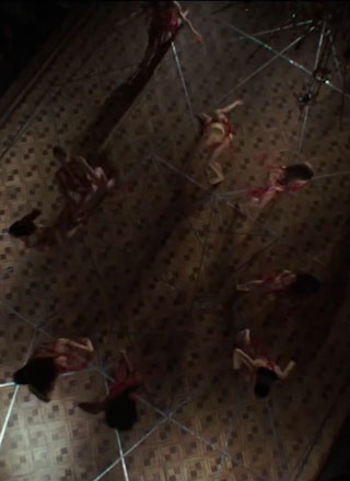 Mme Blanc stretches out her arm in red robes and leads a dance.