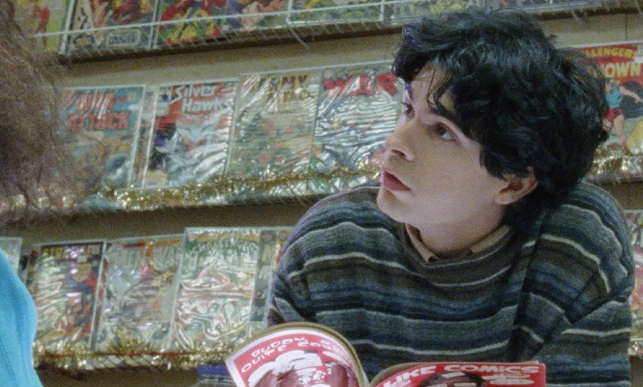 Daniel Zolghadri behind the counter at a comic-book store holding an open magazine.
