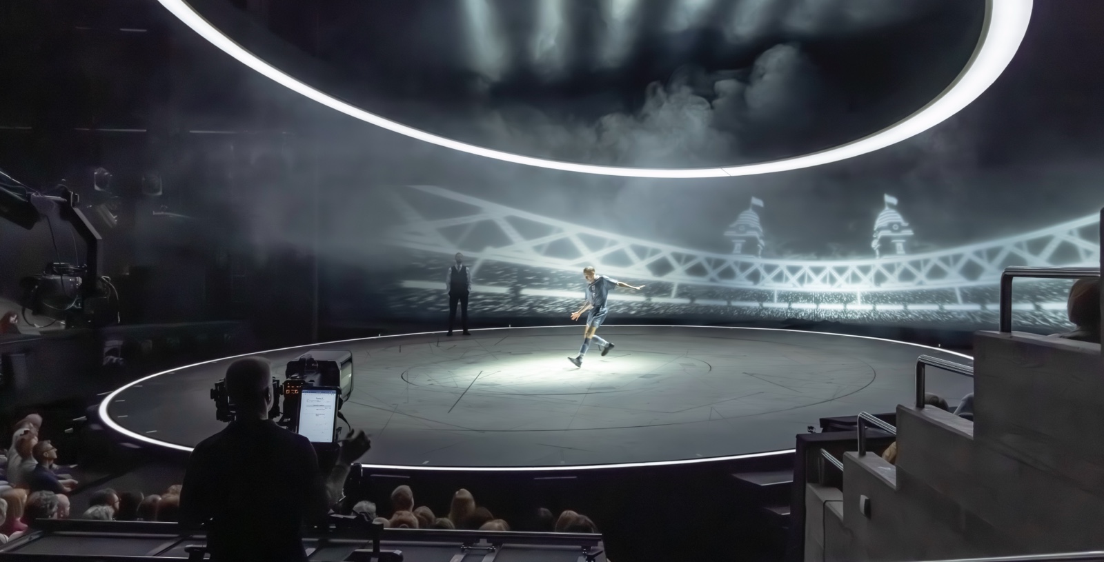 A photograph of the camera rehearsal for Small Island, featuring a camera operators filming three actors standing on stage. 