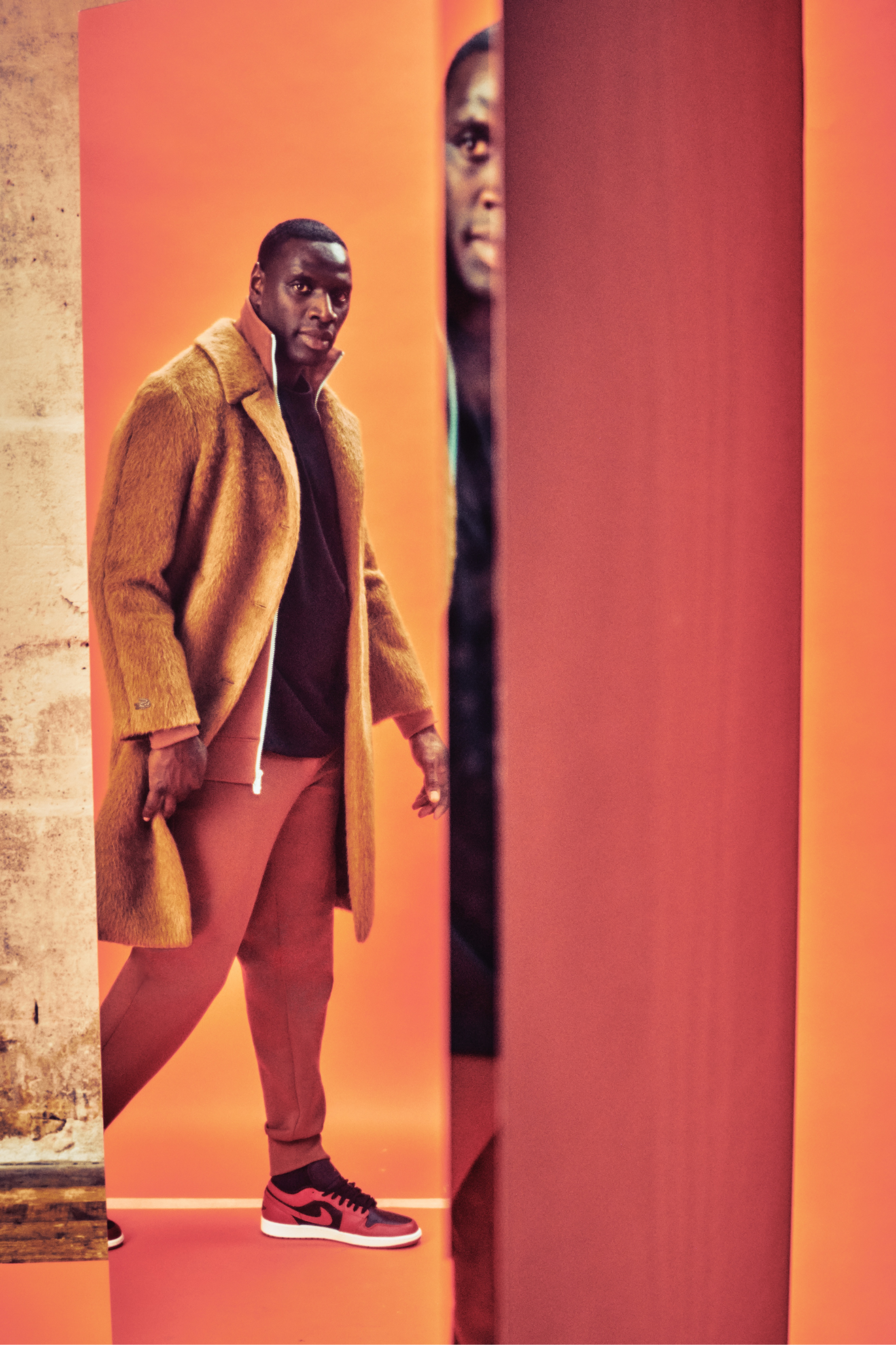 More reflections of Sy, this time in a long orange-brown coat and red Jordan 1s.